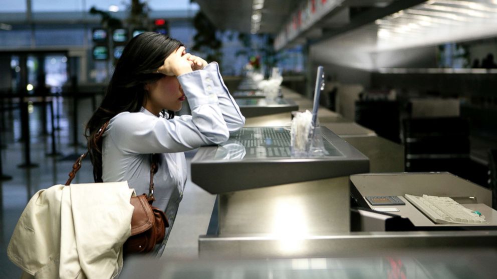 A frustrated businesswoman stands at the check-in counter in an airport, in this undated photo.