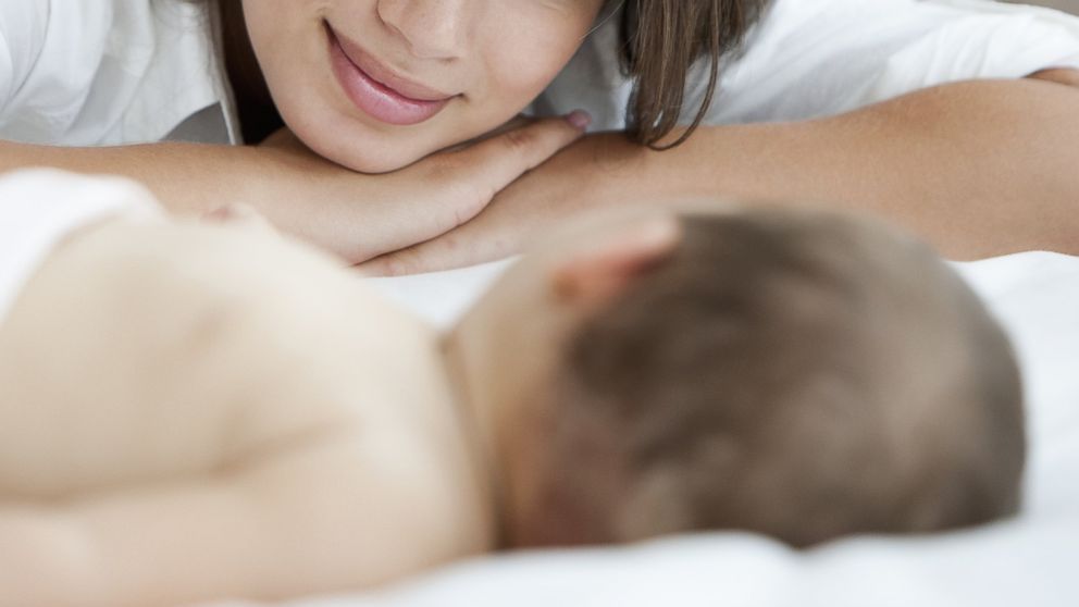 A mother admires her sleeping baby in an undated stock photo.