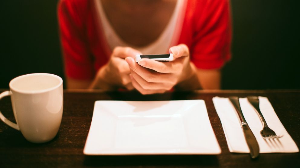 PHOTO: A young woman uses a smartphone in a restaurant in this undated stock photo.