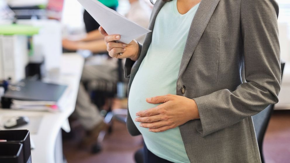A pregnant businesswoman working in office in this stock photo. 