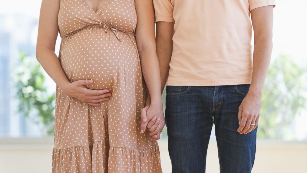 A young pregnant woman holds her partner's hand in an undated stock image.