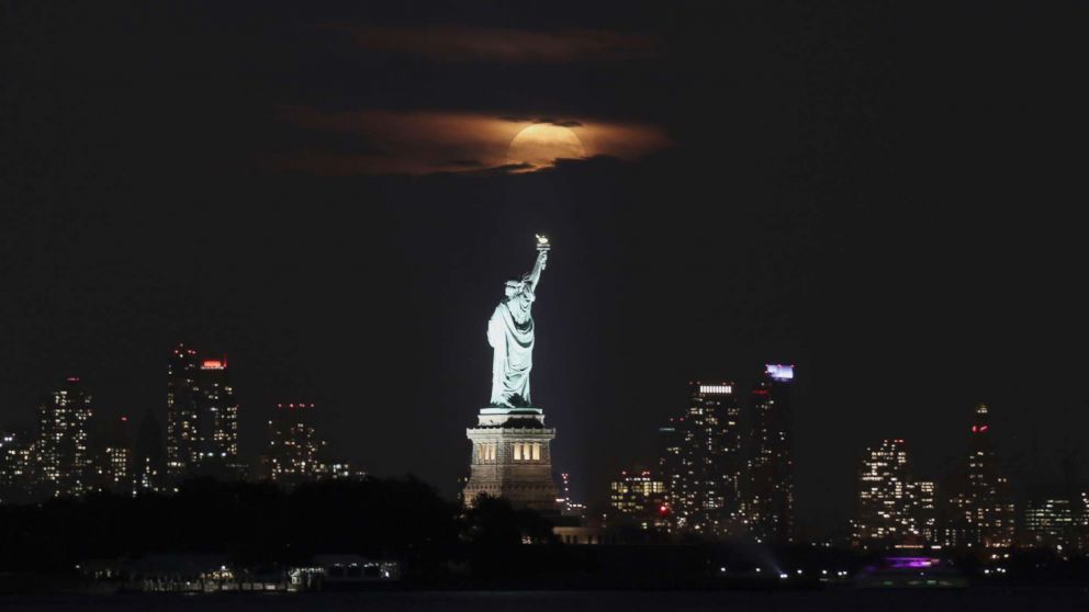 PHOTO: The harvest moon rises above the Statue of Liberty in New York City, Oct. 5, 2017, as seen from Jersey City, NJ.  