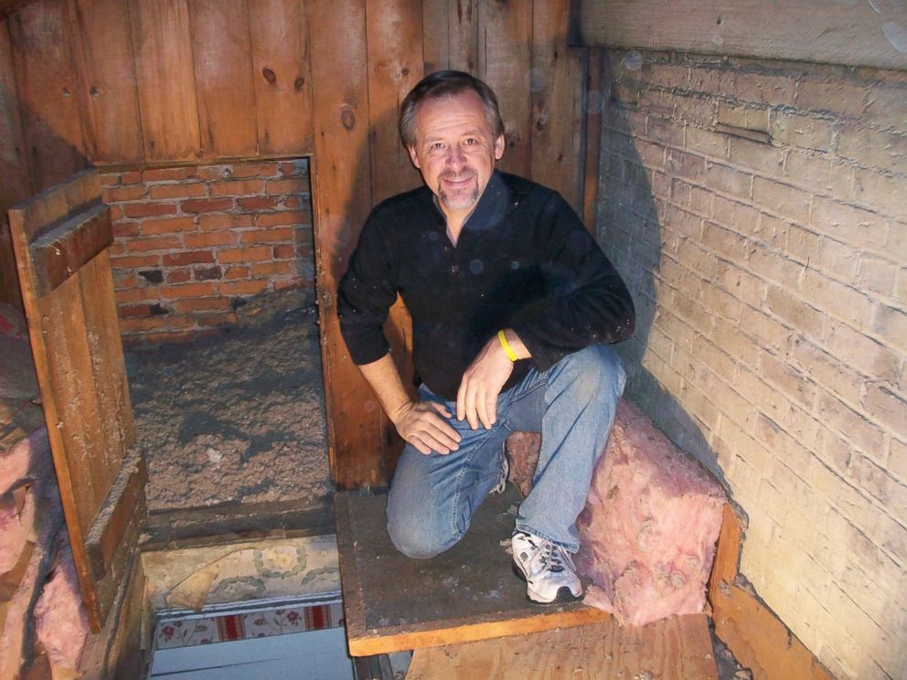 PHOTO: Innkeeper Mike Venturini sits in front of the Munro House's secret passage which leads to rooms where 12 adults could fit.