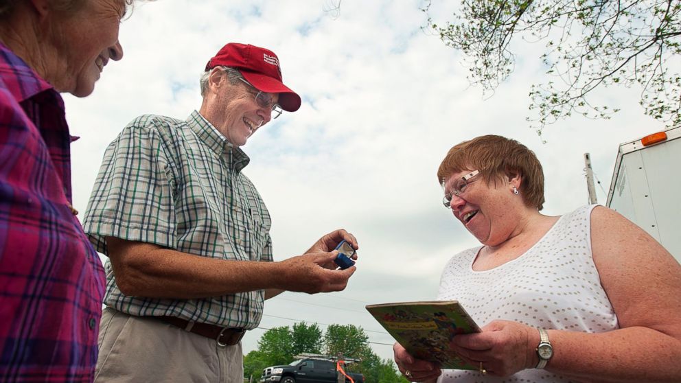 Roger S. Austin, left, presents a diamond ring to Beverly J. Parmeter Wednesday along Route 68 in Lisbon where a historic log cabin was in the process of being dismantled and moved to the St. Lawrence Power & Equipment museum in Madrid. 