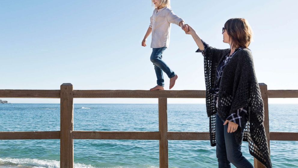 PHOTO: In this undated stock photo, a young boy walking along a fence holding his mothers hand in Laguna Beach, Calif.