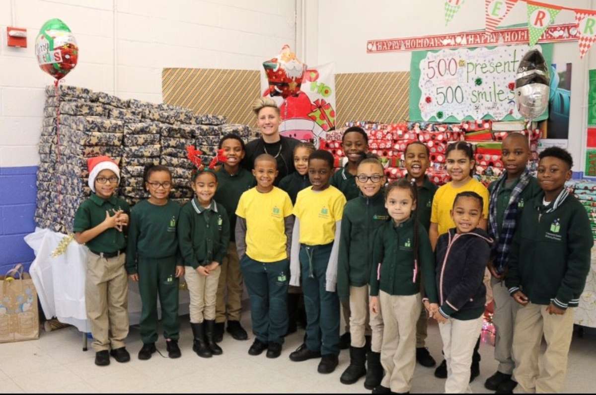 PHOTO: Jennifer Olawski poses with students in front of their presents at Community Charter School of Paterson.