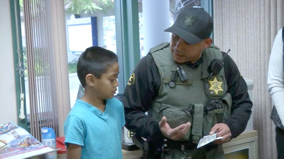 PHOTO: Orange County sheriff's deputy hands $100 to a second grader who's going through a tough time at home.