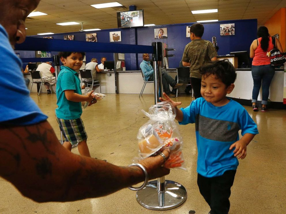 PHOTO: Volunteer Monroy Martinez, left, hands out a free to-go lunch to a young boy at the St. Mary's Food Bank Alliance due to the Arizona teachers strike, April 26, 2018, in Phoenix.