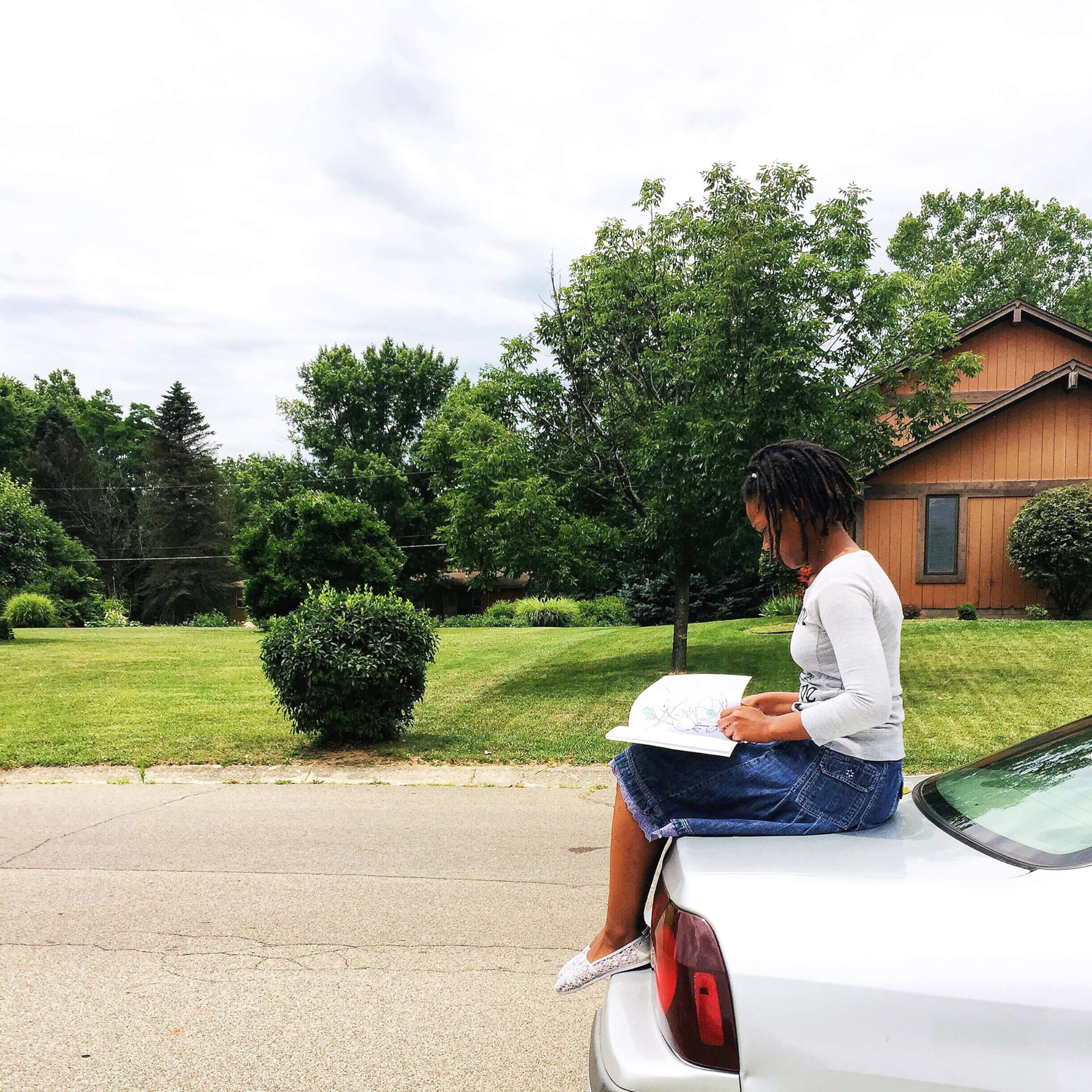 PHOTO: Nakiah White, 12, reads a book outside.
