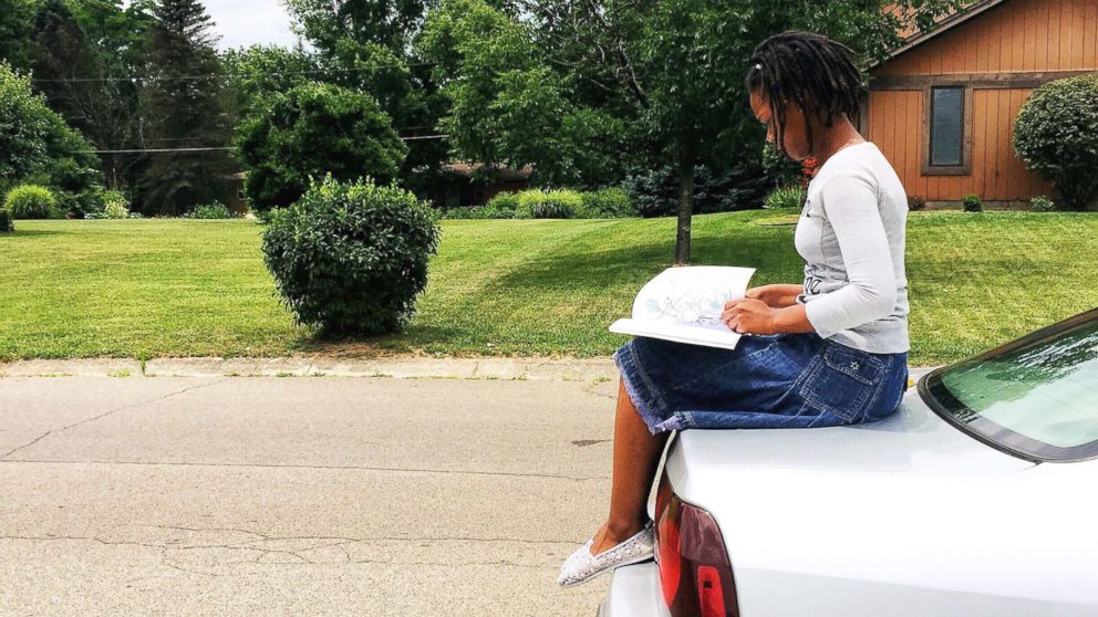 PHOTO: Nakiah White, 12, reads a book outside.