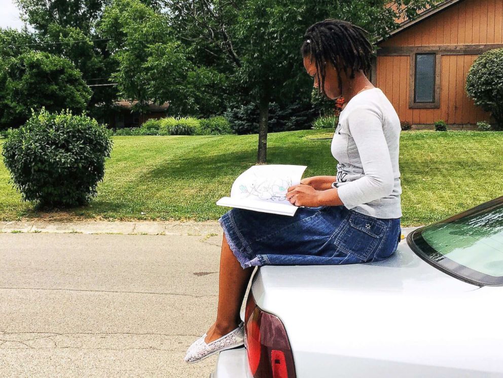 PHOTO: Nakiah White, 12, reads a book outside.