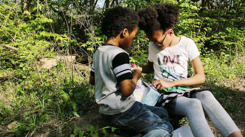 PHOTO: Samuel White, 7, and Ava White, 10, study together in the outdoors.