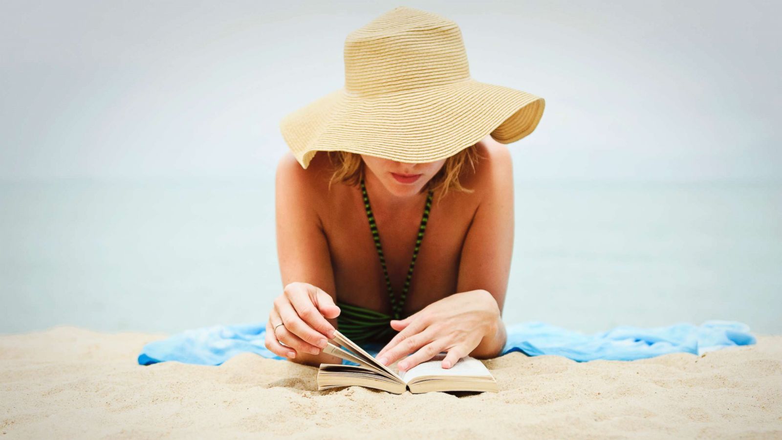 PHOTO: A young woman reads a book on the beach in an undated stock photo.