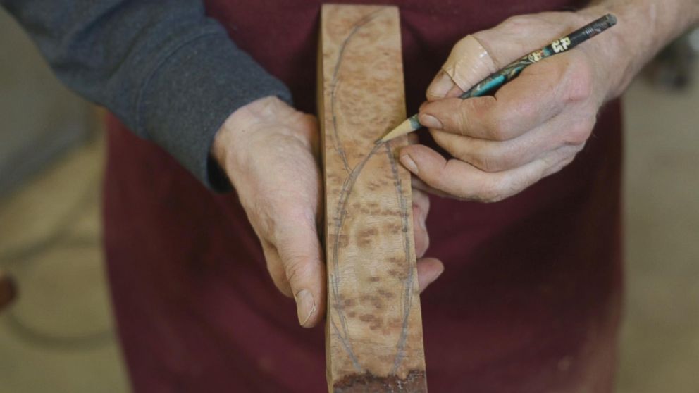 PHOTO: Woodworker Norm Sartorius sketching out an outline of a spoon on a plank of wood.