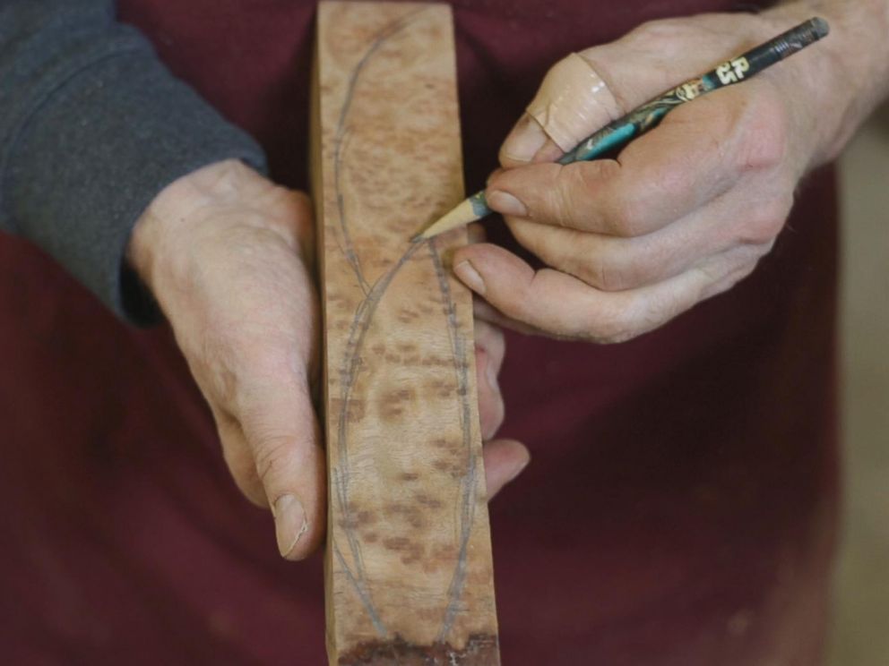 PHOTO: Woodworker Norm Sartorius sketching out an outline of a spoon on a plank of wood.