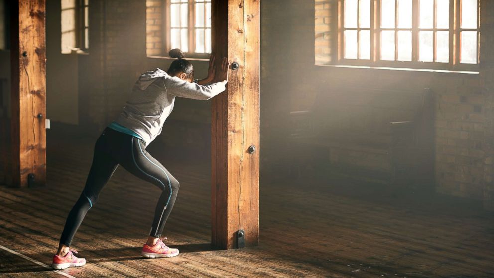 A woman stretches at a gym in this stock photo.