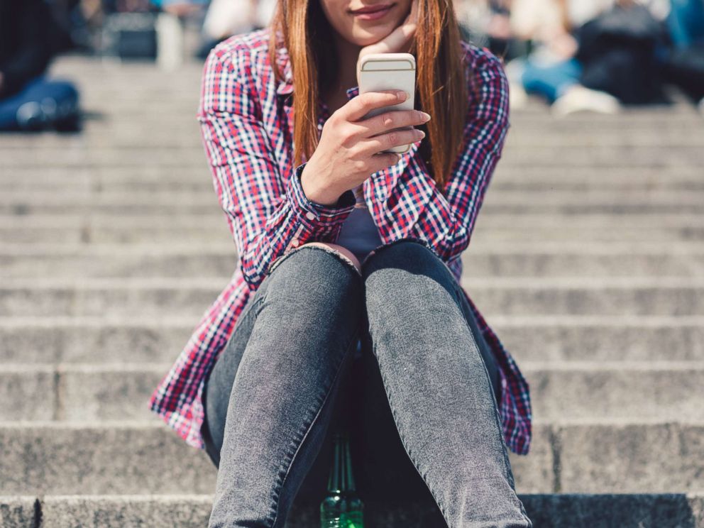 PHOTO: In this undated stock photo, a young woman sitting on the stairs while she is text messaging.