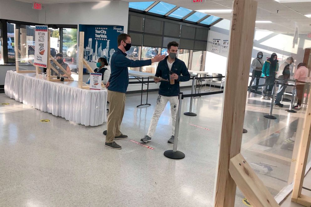 PHOTO: An election official directs a voter to the check-in desk at an early voting center in Minneapolis, Sept. 18, 2020.