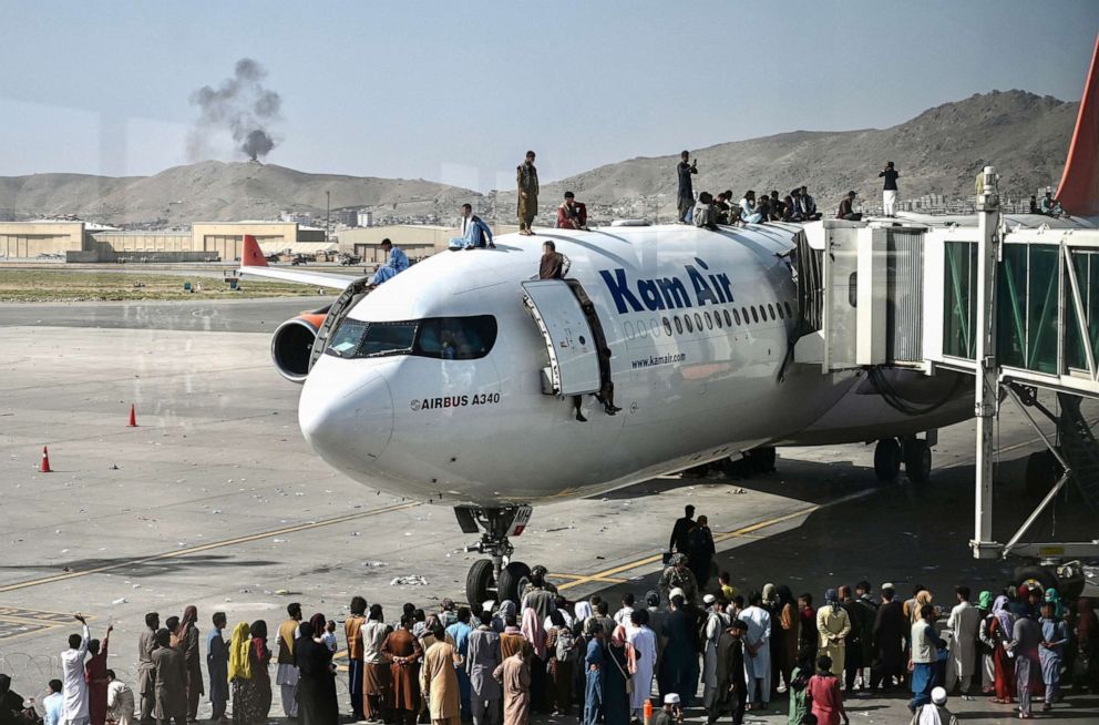 PHOTO: In this Aug. 16, 2021, file photo, Afghan people climb atop a plane as they wait at the Kabul airport in Kabul, Afghanistan.