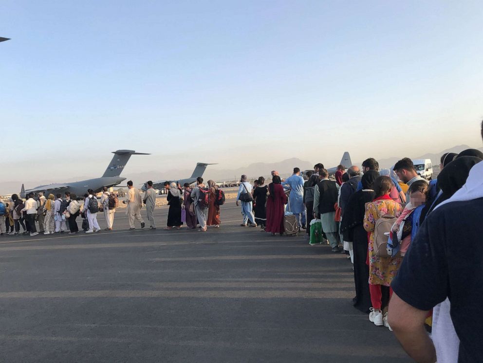 PHOTO: In this Aug. 24, 2021, file photo, people queue up to board a military aircraft at Kabul airport in Kabul, Afghanistan.
