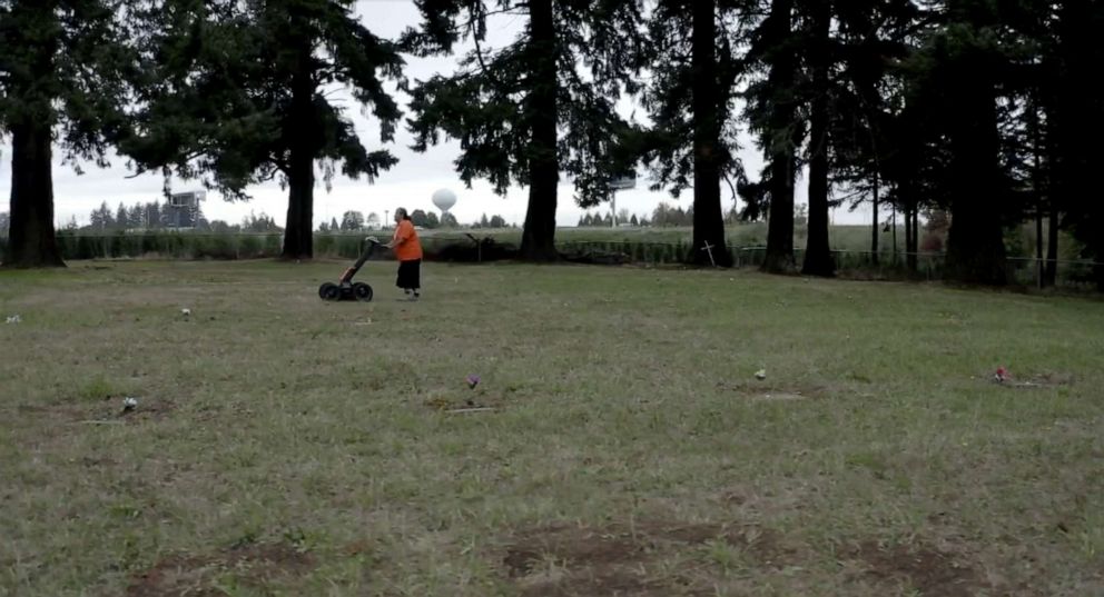 PHOTO: Marsha F. Small uses ground penetrating radar technology to look for remains of children at the Chemawa Indian School in Salem, Ore., Markers on the ground are placed where graves were found.