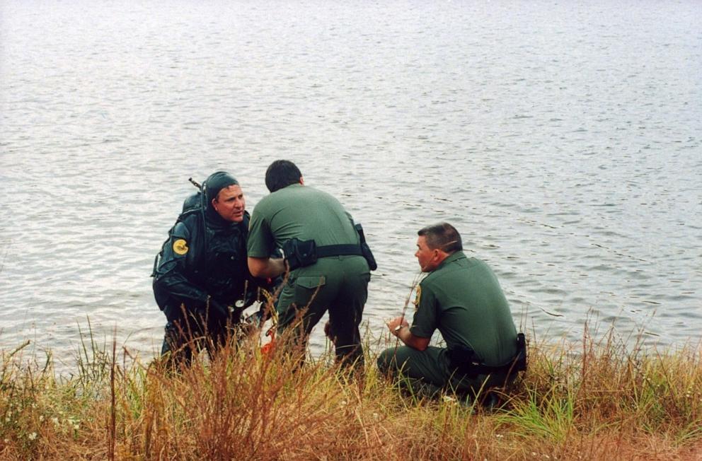 PHOTO: In this 1994 file photo, law enforcement officials, one clad in scuba gear, talk as they comb the water's bottom for the car of Susan Smith, who admitted to drowning her sons Michael & Alex in her car in John D. Long Lake. 