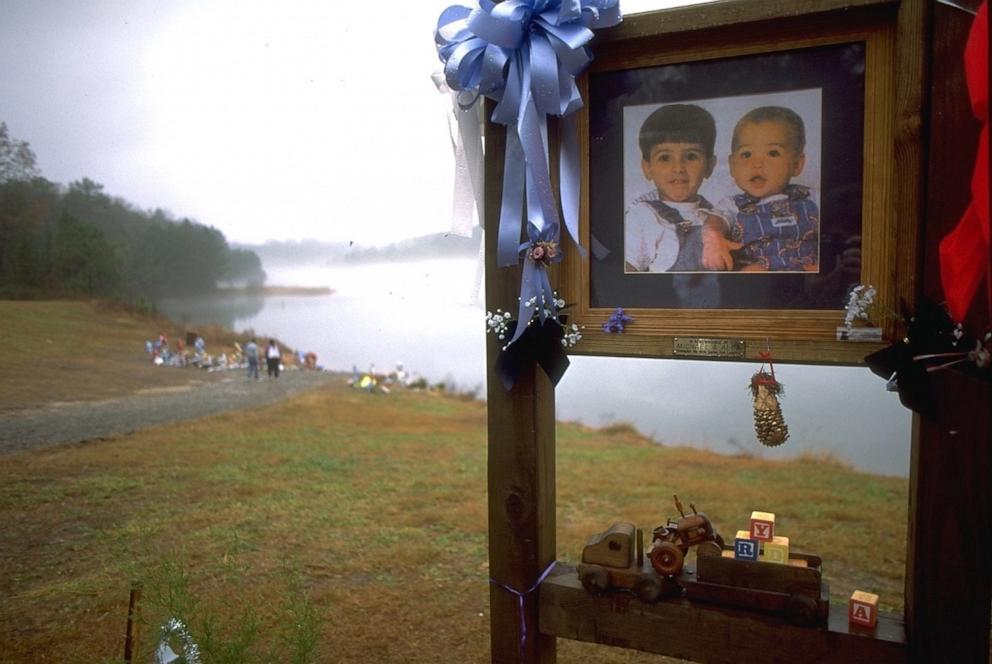 PHOTO: In this 1995 file photo, Michael Daniel Smith and Alexander Tyler Smith are shown on a sign as people place flowers near the lake where the boys were drowned. 