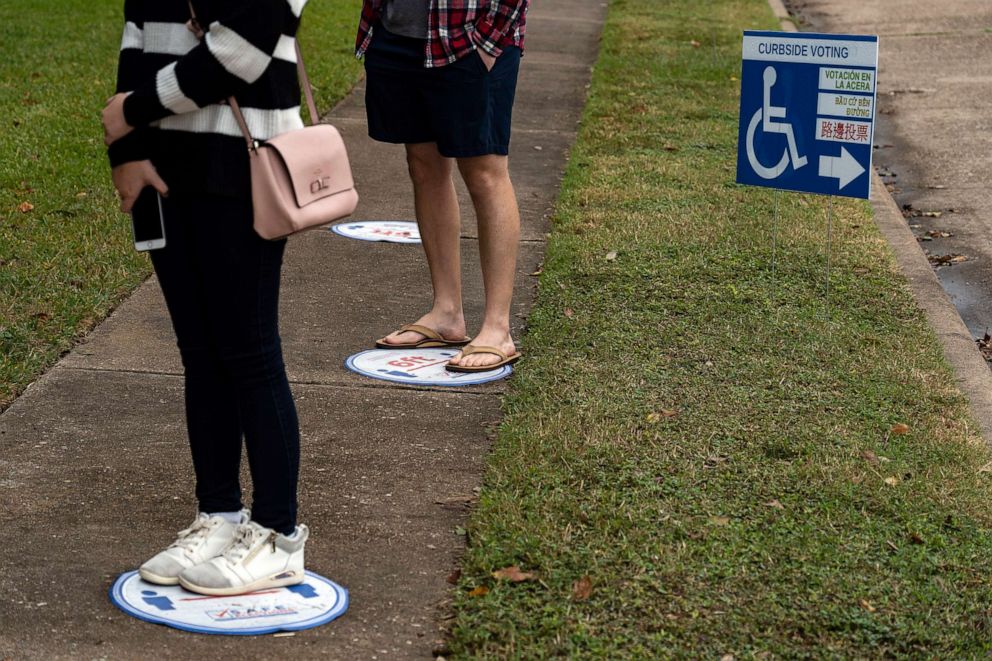 PHOTO: People wait in line on social distancing markers outside an advance voting station  in Houston, Oct. 16, 2020.