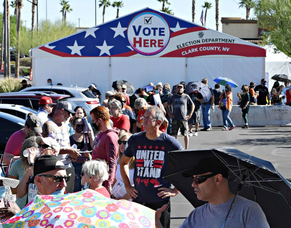 PHOTO: Travis Gardner, center, waits to vote at a shopping center on the first day of in-person early voting on Oct. 17, 2020 in Las Vegas.
