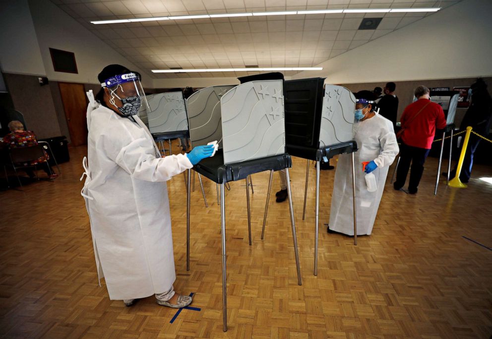 PHOTO: Poll workers wearing PPE sanitize voting booths before each use on the first day of the state's in-person early voting for the general election in Durham, N.C., Oct. 15, 2020.