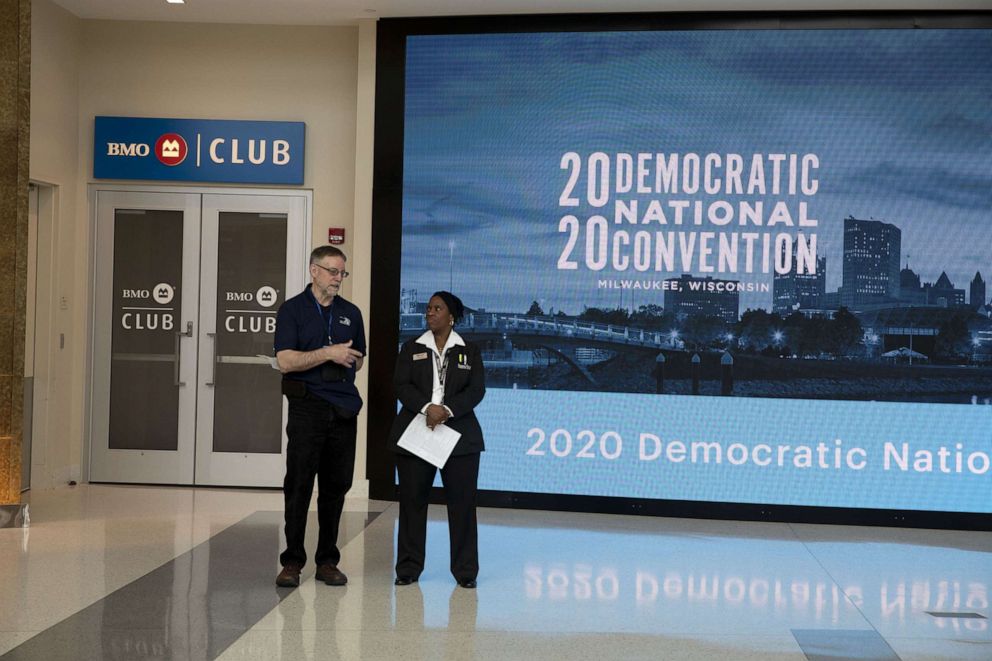 PHOTO: Workers stand near signage during a media walkthrough for the upcoming Democratic National Convention at the Fiserv Forum in Milwaukee, Jan. 7, 2020.