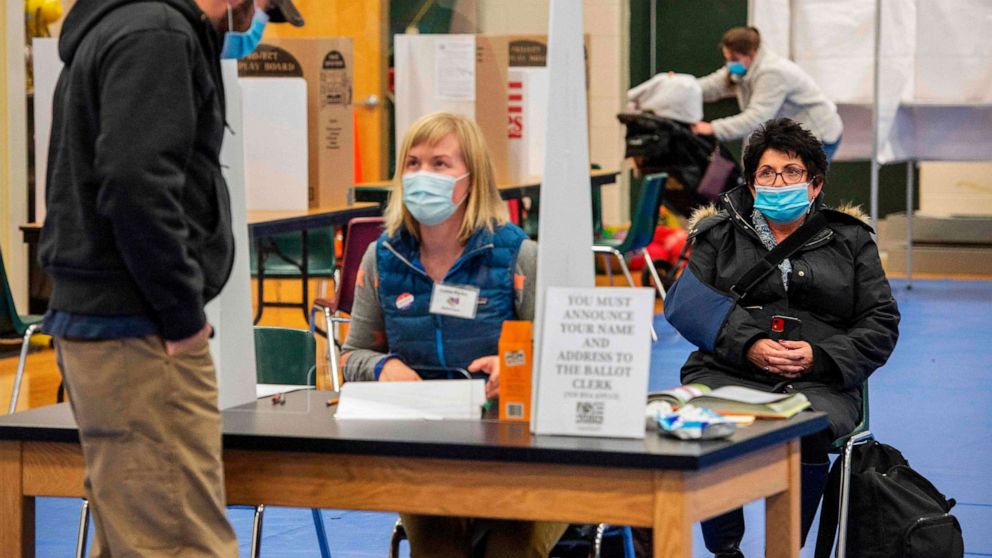 PHOTO: A poll watcher looks on as clerks check voters in at the Captain Samuel Douglass Academy polling station in Brookline, N.H., Nov. 3, 2020.