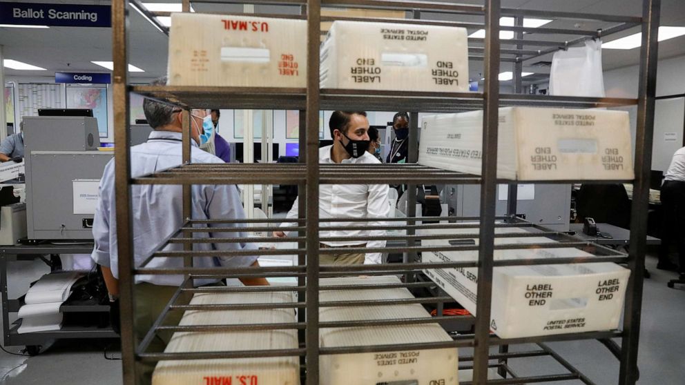 PHOTO: U.S. Postal Service trays are seen as workers of the Miami-Dade County Elections Department feed mail-in ballots in counting machines during the 2020 presidential election in Miami, Nov. 3, 2020.
