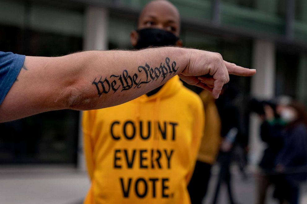 PHOTO: A tattooed phrase from the United States Constitution decorates the arm of Trump supporter Bob Lewis, left, as he argues with a counter protester outside the central counting board at the TCF Center in Detroit, Nov. 5, 2020.