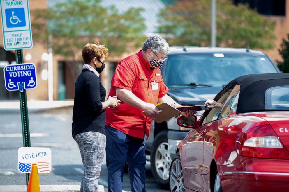 PHOTO: Election workers Tim McLeod and Cybil Usual assist a voter casting a ballot curbside on the first day of early voting at the Office of Elections satellite location at Southpoint in Spotsylvania, Va., Sept. 18, 2020.