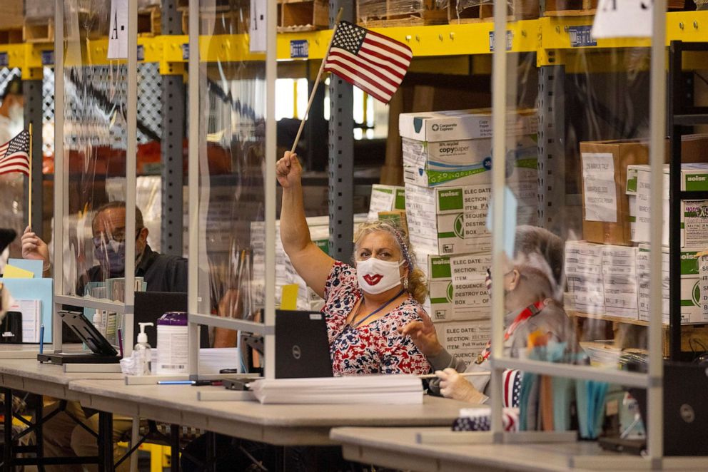 PHOTO:Poll workers wave flags to bring a voter to their location booth at the Registrar of Voters on Election Day in San Diego, Nov. 3, 2020.