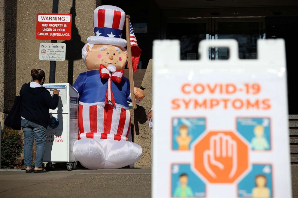 PHOTO: A voter drops off her ballot in a box outside the Santa Clara County registrar of voters office on Oct. 13, 2020, in San Jose, Calif.