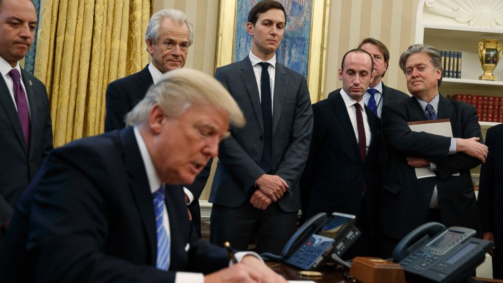 From left, White House Chief of Staff Reince Priebus, National Trade Council adviser Peter Navarro, Senior Adviser Jared Kushner, policy adviser Stephen Miller, and chief strategist Steve Bannon watch as President Donald Trump signs an executive order in the Oval Office of the White House, Jan. 23, 2017, in Washington. 