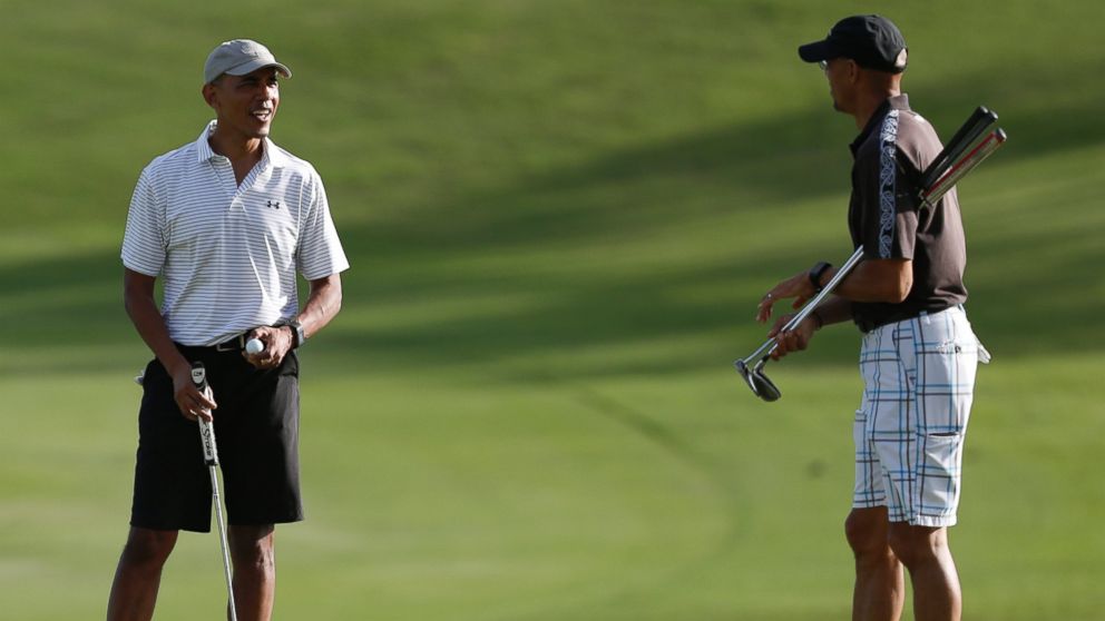 President Barack Obama looks to Darrell Harrington as they golf the 18th green at Kapolei Golf Club, in Kapolei, Hawaii, Wednesday, Dec. 21, 2016. (AP Photo/Carolyn Kaster)