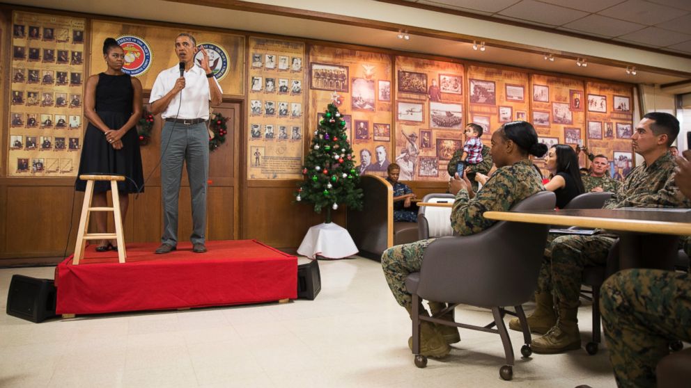 PHOTO: First lady Michelle Obama, left, looks on as President Barack Obama speaks during an event to thank service members and their families at Marine Corp Base Hawaii, on Friday, Dec. 25, 2015, in Kaneohe Bay, Hawaii.