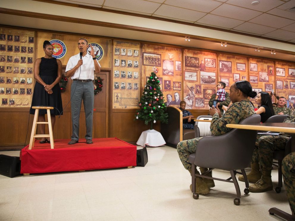 PHOTO: First lady Michelle Obama, left, looks on as President Barack Obama speaks during an event to thank service members and their families at Marine Corp Base Hawaii, on Friday, Dec. 25, 2015, in Kaneohe Bay, Hawaii.