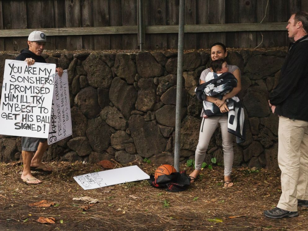 PHOTO: President Barack Obamas motorcade returns from golf as Cheyne Todani, left, holds a sign asking the president to sign a basketball for his son, Friday, Jan. 2, 2015, in Kailua, Hawaii.