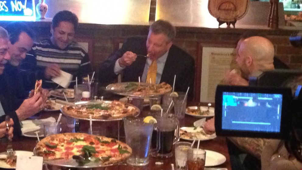 PHOTO: New York City Mayor Bill de Blasio, center, uses a knife and fork to pizza at Goodfellas Pizza in the Staten Island borough of New York, Jan. 10, 2014.