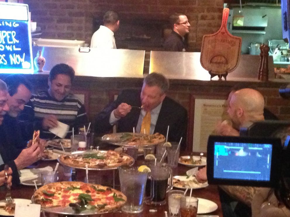 PHOTO: New York City Mayor Bill de Blasio, center, uses a knife and fork to pizza at Goodfellas Pizza in the Staten Island borough of New York, Jan. 10, 2014.