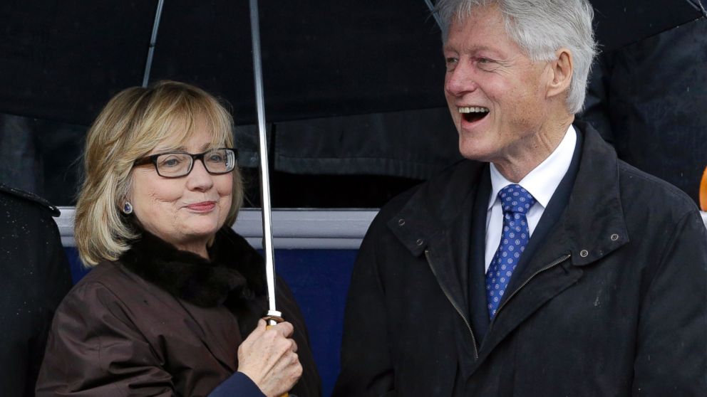 Former Secretary of State Hillary Rodham Clinton, left, and former President Bill Clinton stand under an umbrella during inaugural ceremonies for Virginia Gov. Terry McAuliffe at the Capitol in Richmond, Va., Jan. 11, 2014. 