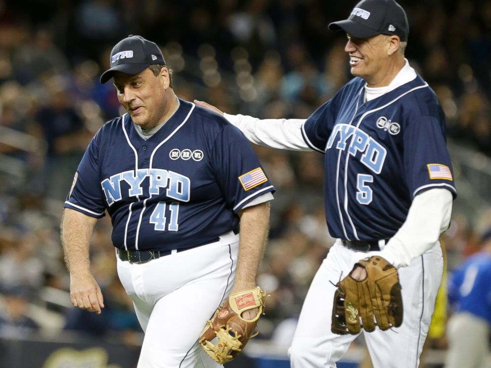 PHOTO: New Jersey Gov. Chris Christie, left and Buffalo Bills coach Rex Ryan, right, celebrate as they head to the dugout during the first inning of the "True Blue" benefit celebrity softball game at Yankee Stadium, June 3, 2015, in New York.