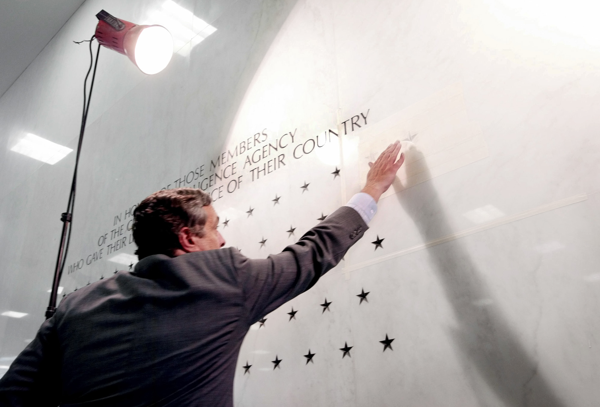 PHOTO: Former Director of the Central Intelligence Agency George Tenet reaches out to touch a five-pointed star freshly carved into the marble-faced lobby wall of CIA headquarters in Langley, Va., May 23, 2002. 
