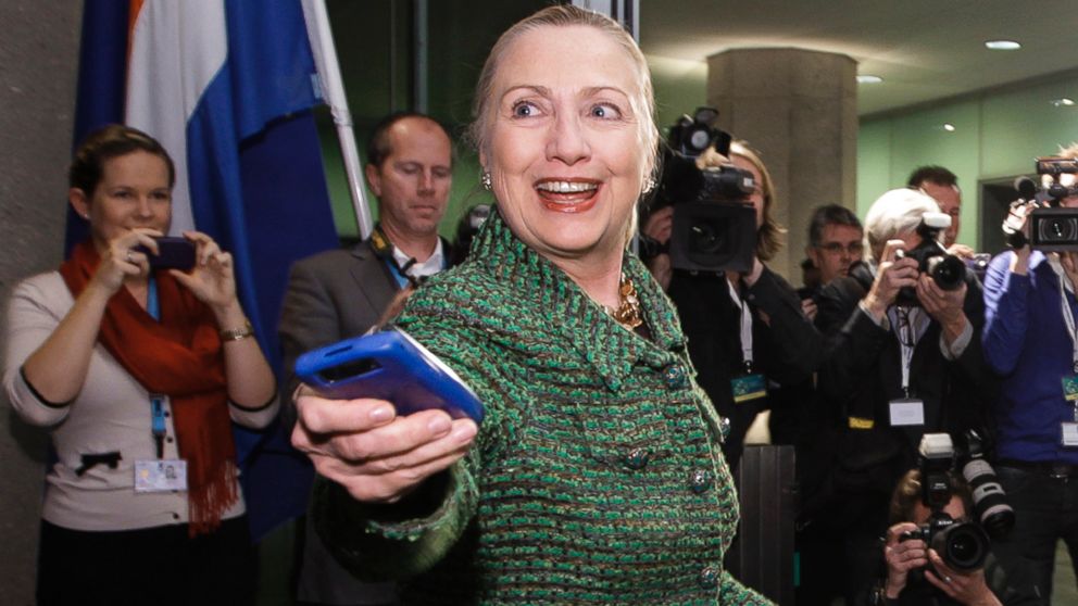 In this Dec. 8, 2011, file photo, then-U.S. Secretary of State Hillary Rodham Clinton hands off her mobile phone after arriving to meet with Dutch Foreign Minister Uri Rosenthal at the Ministry of Foreign Affairs in The Hague, Netherlands. 