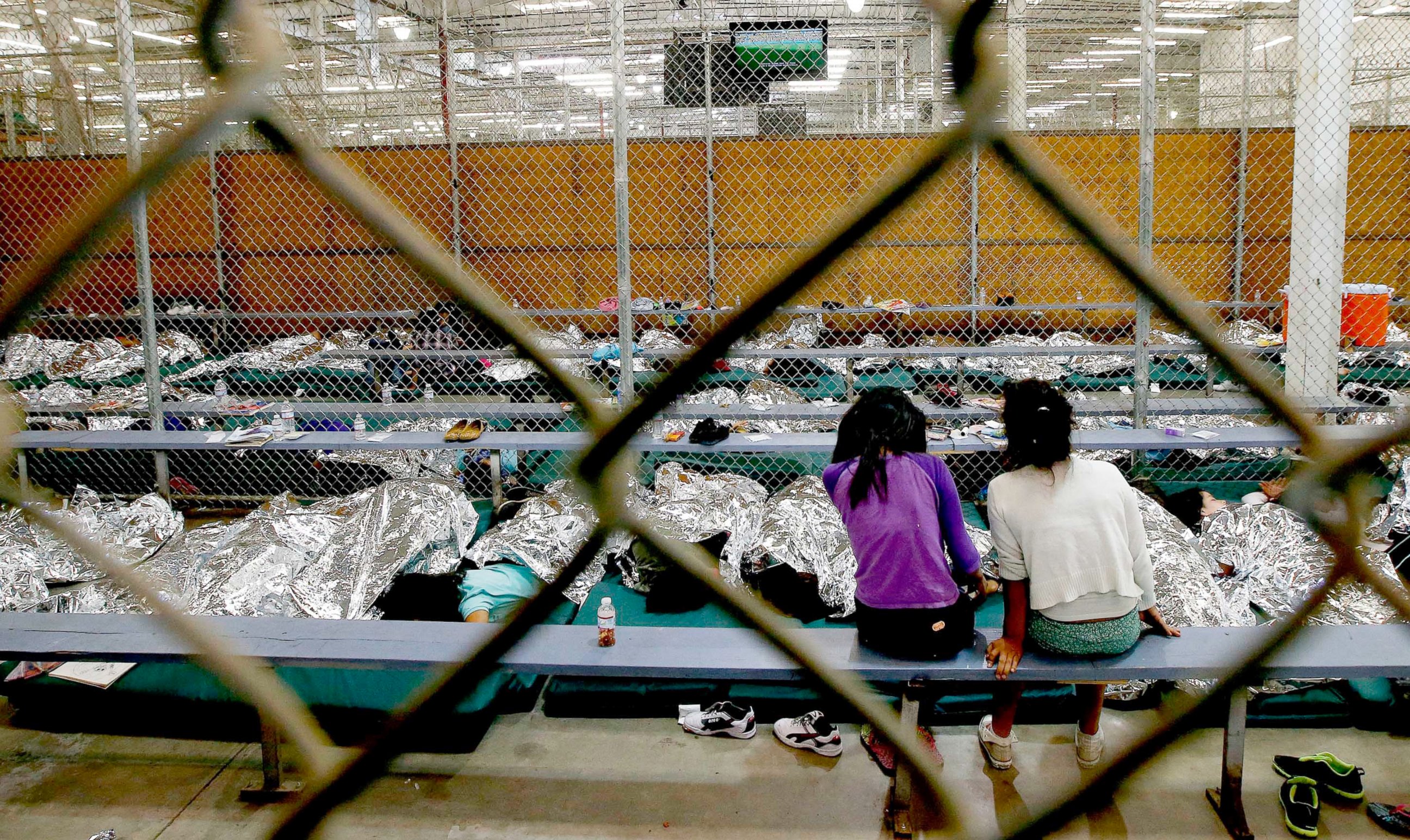 PHOTO: Two young girls watch a World Cup soccer from their holding area where hundreds of immigrant children are being processed at the U.S. Customs and Border Protection Nogales Placement Center, June 18, 2014, in Nogales, Ariz.