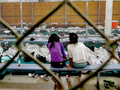 PHOTO: Two young girls watch a World Cup soccer from their holding area where hundreds of immigrant children are being processed at the U.S. Customs and Border Protection Nogales Placement Center, June 18, 2014, in Nogales, Ariz.